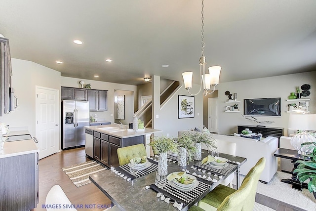 kitchen with stainless steel appliances, pendant lighting, light countertops, and a center island with sink