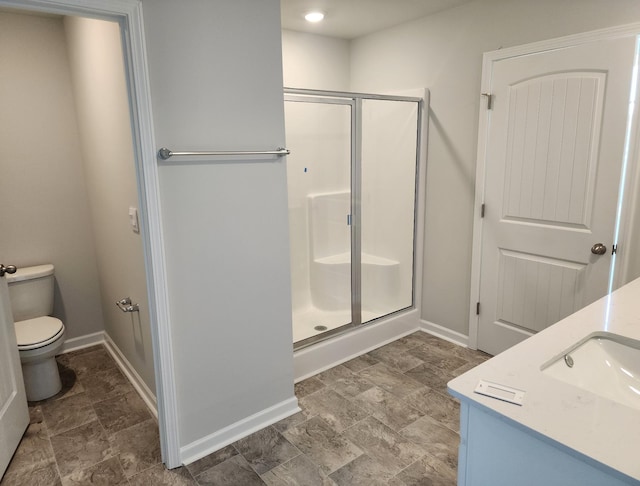 bathroom with toilet, a stall shower, vanity, and baseboards