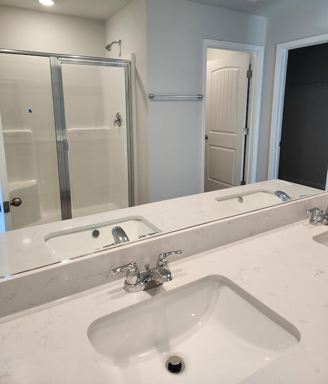 full bathroom with a stall shower, a sink, and double vanity