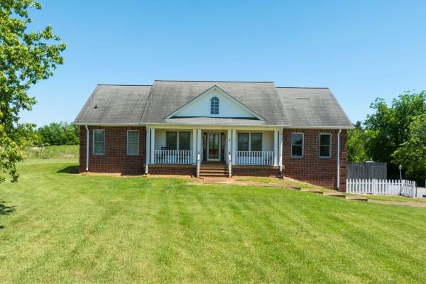 view of front of home featuring covered porch, brick siding, and a front lawn