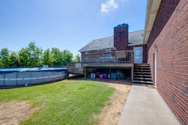 view of yard featuring stairs, a wooden deck, and a covered pool