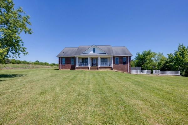 view of front facade with covered porch, a front yard, and fence