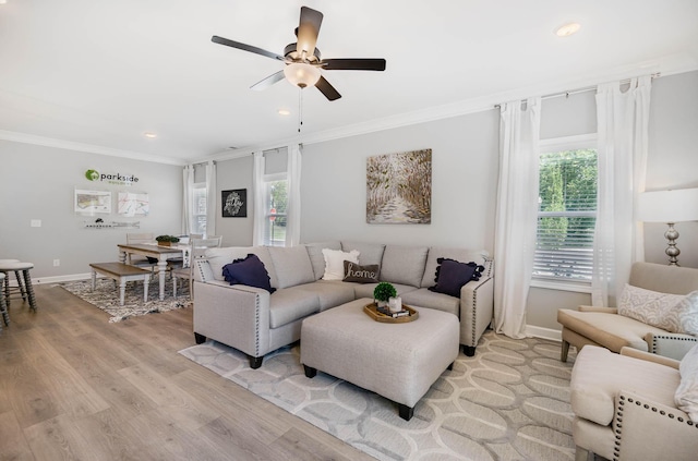 living room featuring recessed lighting, light wood-style flooring, ornamental molding, a ceiling fan, and baseboards