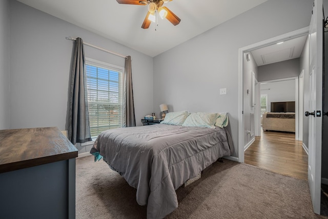 carpeted bedroom featuring attic access, a ceiling fan, and baseboards