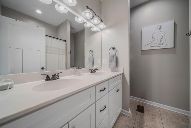 full bathroom with double vanity, tile patterned flooring, baseboards, and a sink