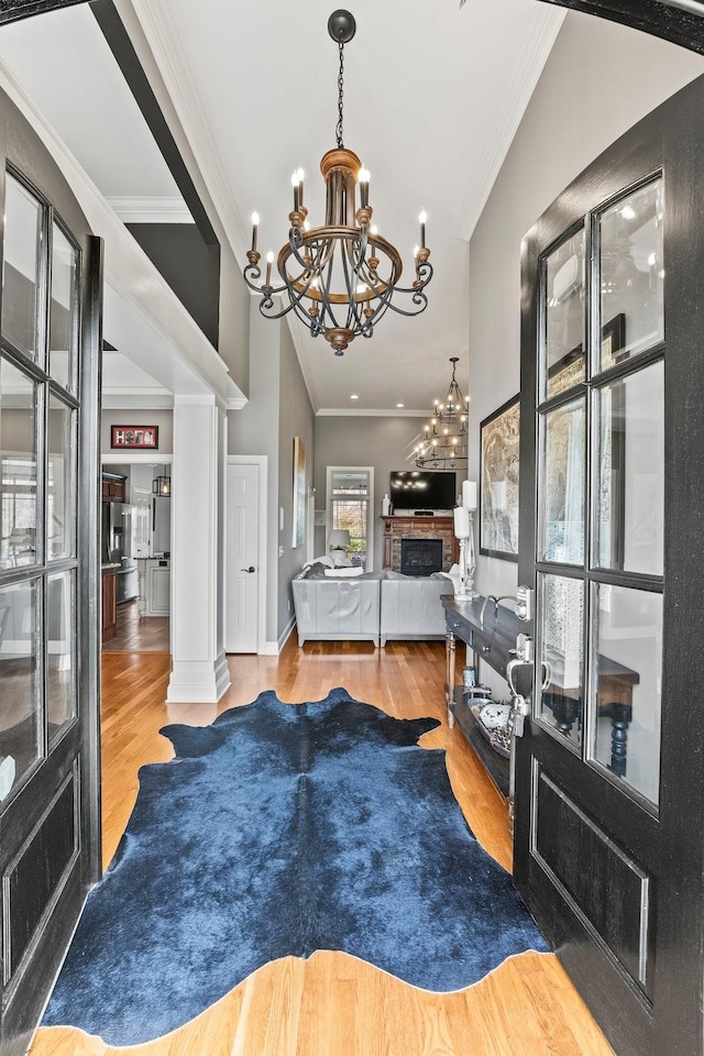 interior space featuring a chandelier, a fireplace, wood finished floors, ornamental molding, and decorative columns