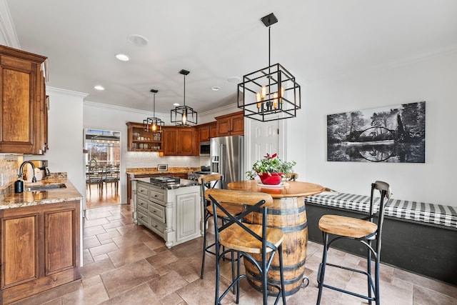 kitchen featuring light stone counters, a sink, appliances with stainless steel finishes, backsplash, and brown cabinets