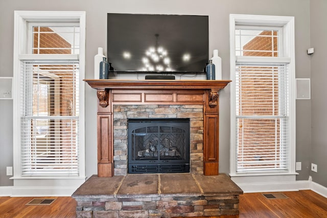 interior details featuring baseboards, visible vents, wood finished floors, and a stone fireplace