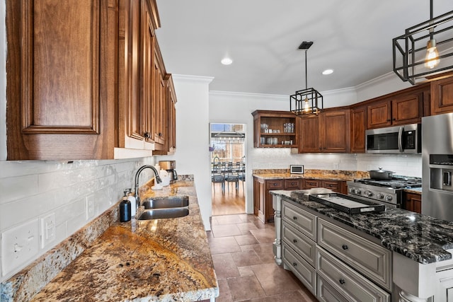 kitchen featuring dark stone countertops, appliances with stainless steel finishes, a sink, and decorative light fixtures