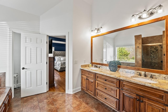 ensuite bathroom with lofted ceiling, double vanity, a sink, and connected bathroom