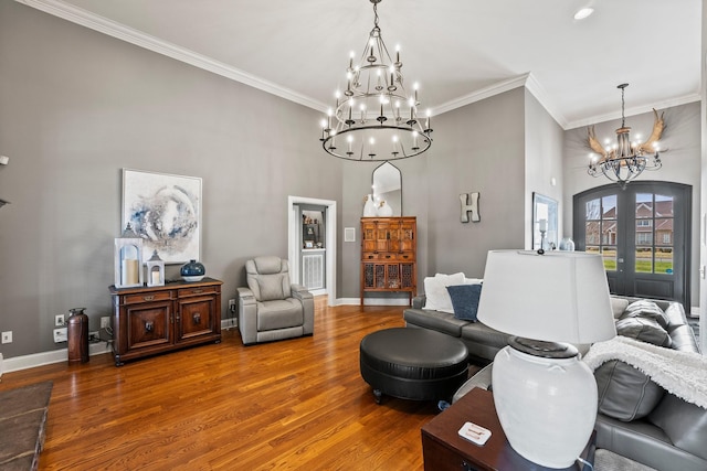 sitting room featuring french doors, crown molding, wood finished floors, a chandelier, and baseboards