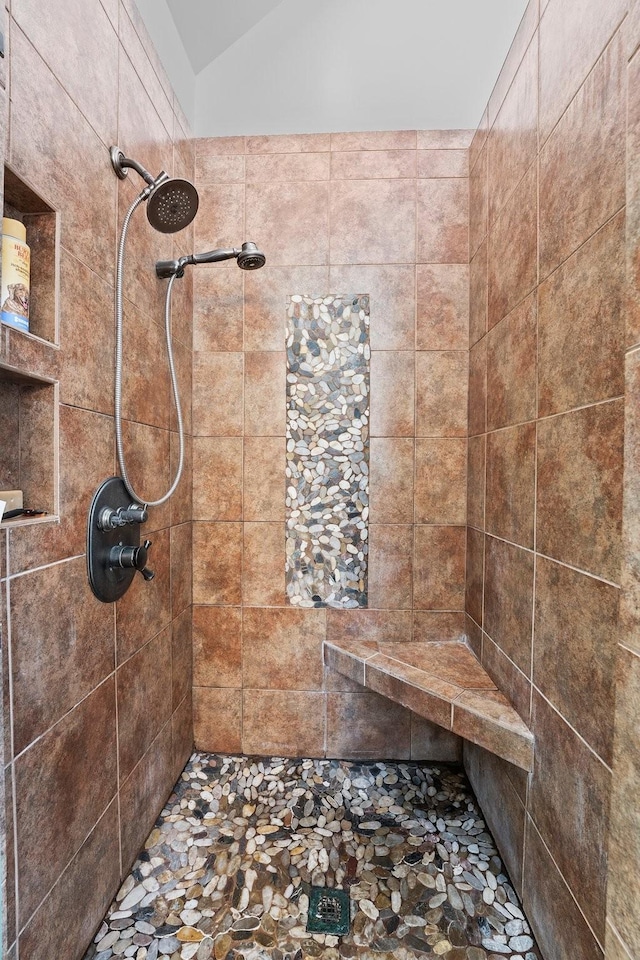 bathroom with a tile shower and vaulted ceiling