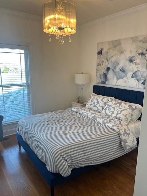 bedroom with ornamental molding, a chandelier, and dark wood-style floors