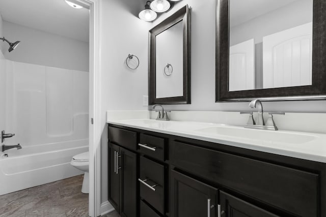 bathroom with double vanity, shower / tub combination, a sink, and toilet