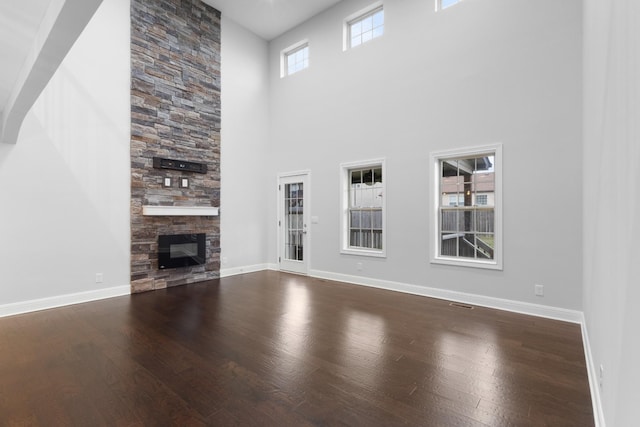 unfurnished living room featuring a fireplace, baseboards, and wood finished floors