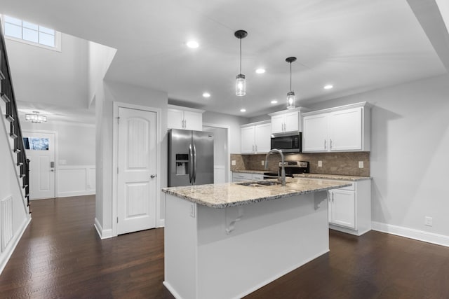 kitchen featuring hanging light fixtures, appliances with stainless steel finishes, a sink, and white cabinets