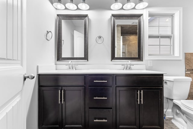 full bathroom with double vanity, a sink, and toilet