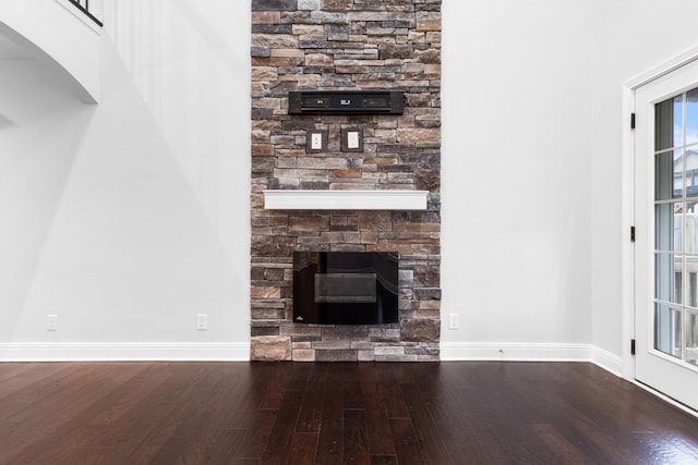 unfurnished living room featuring a fireplace, baseboards, and wood finished floors