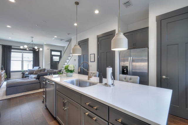 kitchen featuring visible vents, dark wood-style flooring, a sink, stainless steel appliances, and open floor plan