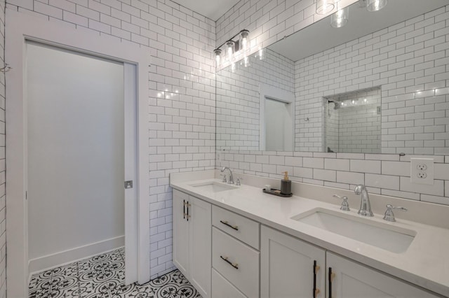 bathroom with a tile shower, tile patterned floors, tile walls, and a sink