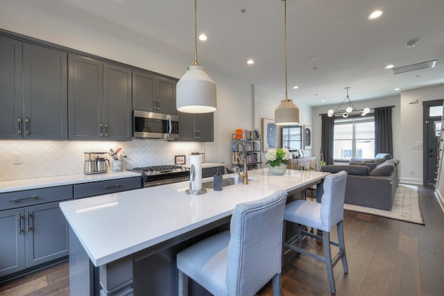 kitchen featuring light countertops, dark wood-style floors, tasteful backsplash, and appliances with stainless steel finishes