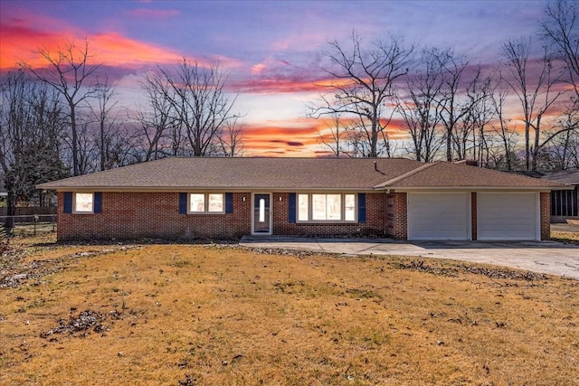 ranch-style house with concrete driveway, brick siding, a lawn, and an attached garage