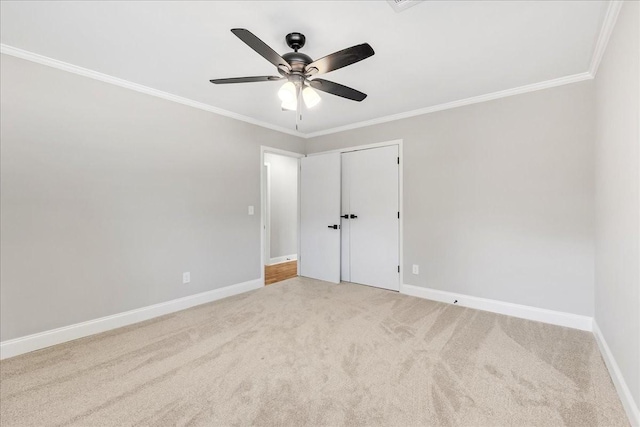 spare room featuring ornamental molding, a ceiling fan, light colored carpet, and baseboards