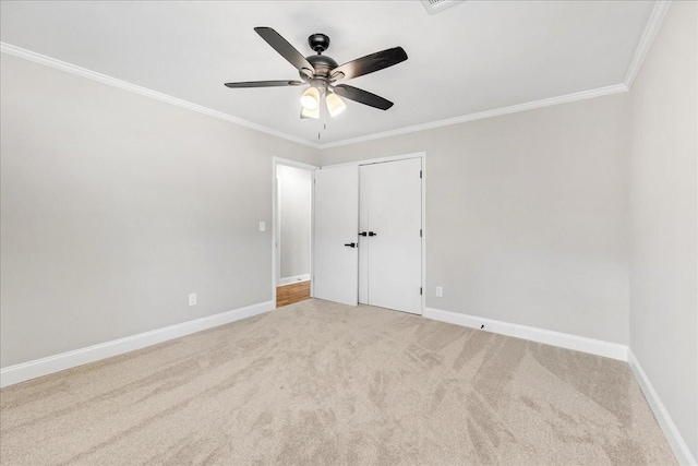 unfurnished bedroom featuring ornamental molding, a ceiling fan, light colored carpet, and baseboards