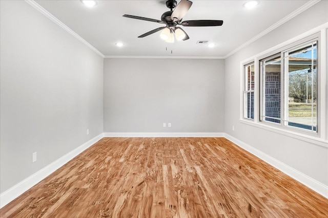 spare room with crown molding, visible vents, light wood-style floors, a ceiling fan, and baseboards