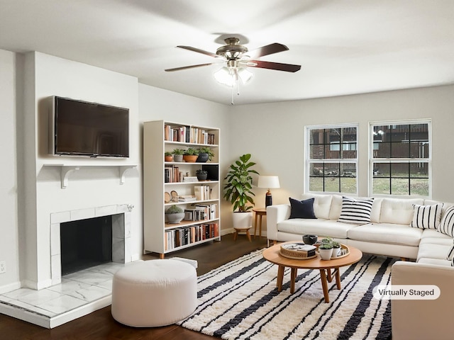 living area with wood finished floors, a tile fireplace, and a ceiling fan