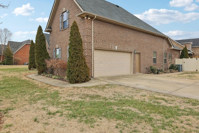 view of side of property featuring a garage, a lawn, concrete driveway, roof with shingles, and brick siding