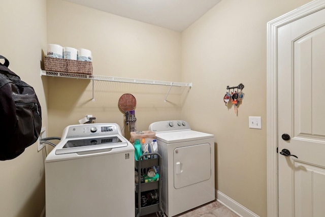 clothes washing area featuring laundry area, washer and clothes dryer, and baseboards