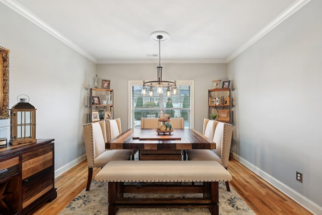 dining room with light wood-style flooring, a notable chandelier, visible vents, baseboards, and crown molding