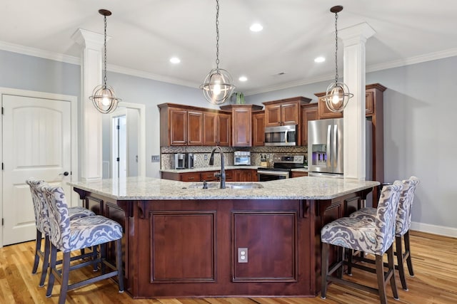 kitchen featuring appliances with stainless steel finishes, a breakfast bar, pendant lighting, and a sink