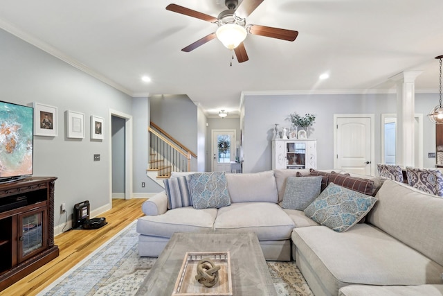 living room with baseboards, ornate columns, stairs, crown molding, and light wood-style floors