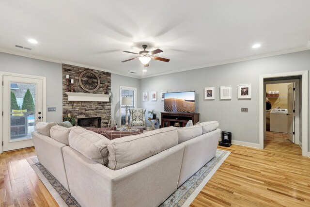 living room with ornamental molding, light wood finished floors, a fireplace, and visible vents