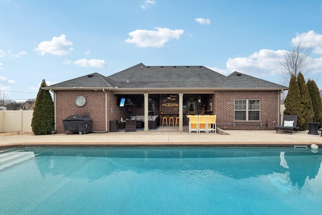 outdoor pool with fence, a bar, area for grilling, and a patio