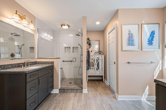 bathroom with a stall shower, vanity, and baseboards