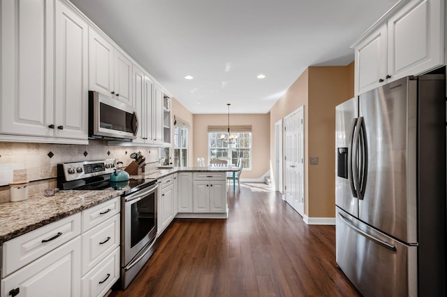 kitchen featuring appliances with stainless steel finishes, light stone counters, hanging light fixtures, a peninsula, and white cabinetry