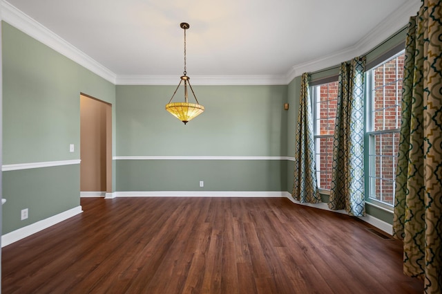 spare room featuring dark wood-style floors, crown molding, and baseboards