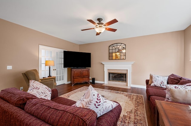 living room with a fireplace with flush hearth, ceiling fan, dark wood finished floors, and baseboards