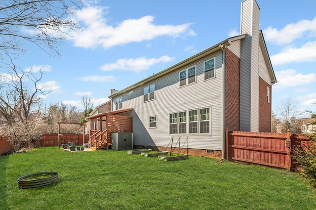 rear view of property featuring a lawn, a fenced backyard, a chimney, crawl space, and stairs