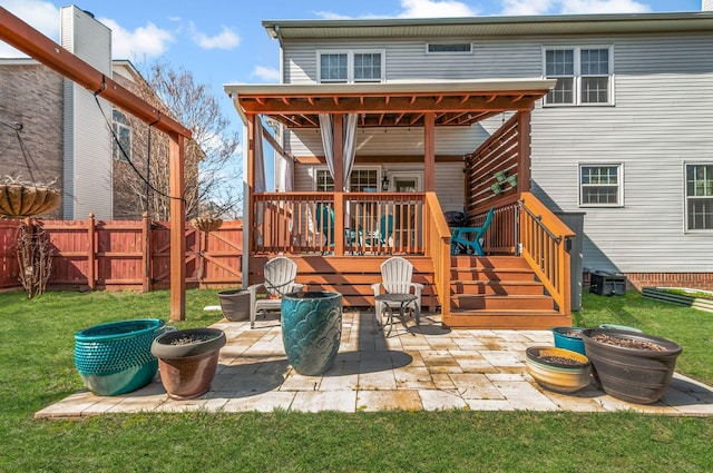 rear view of property with a patio, a lawn, and fence