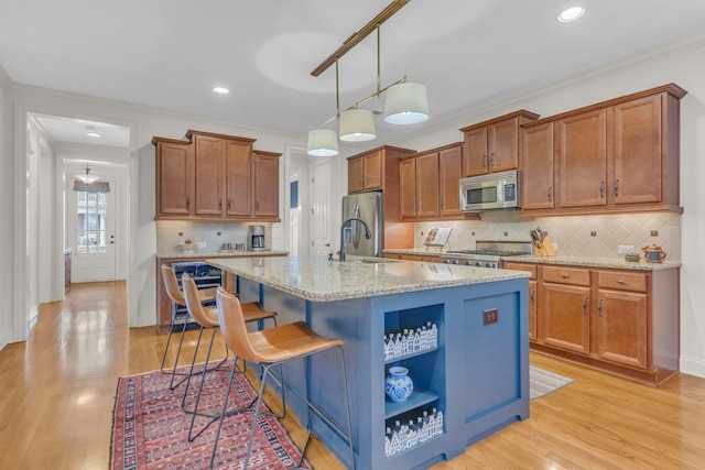 kitchen featuring appliances with stainless steel finishes, a sink, a center island with sink, and brown cabinets