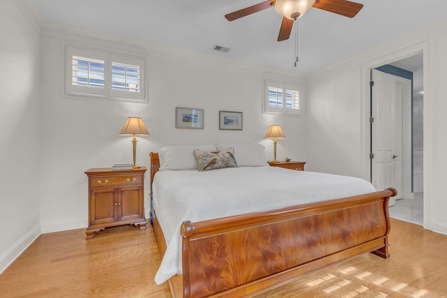 bedroom with light wood finished floors, baseboards, visible vents, and crown molding