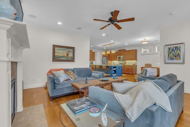 living area featuring crown molding, recessed lighting, a fireplace with flush hearth, light wood-style floors, and baseboards