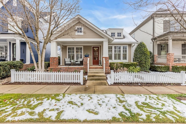 view of front of home with covered porch, a fenced front yard, and brick siding