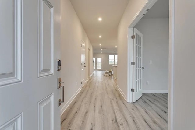 hall with light wood-style floors, recessed lighting, and baseboards