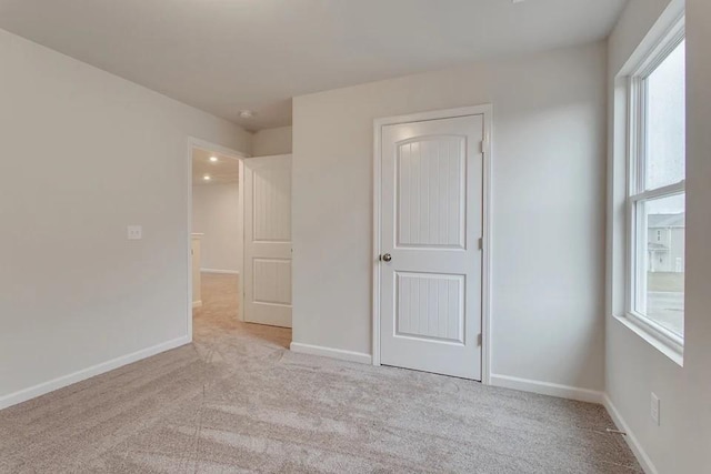 unfurnished room with light carpet and baseboards