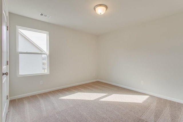 carpeted spare room featuring visible vents and baseboards